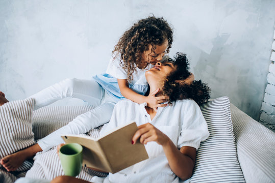 Kid Kissing Mom On Cozy Sofa