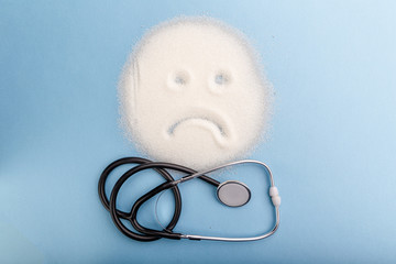 Sugar is dangerous. Stethoscope on the table with sugar face. Sweet disease dependence