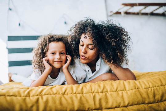 Ethnic Young Woman Telling Story Kid In Bedroom