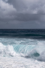 Kaimu Beach, Hawaii, USA. - January 14, 2020: Portrait of Dark ocean under heavy gray rain cloudscape produces white surf when azure wave turns and crashes.