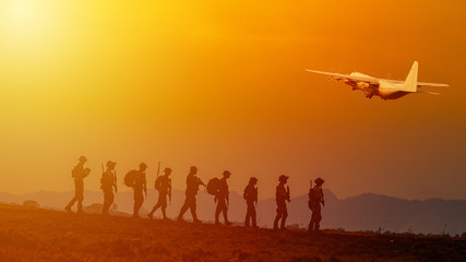 Fototapeta na wymiar Silhouette of military rangers and Helicopter with soldier on the top of mountain at sunset 