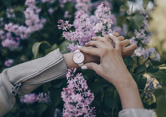 Fototapeta premium Stylish white watch on woman hand in lilac flowers
