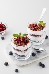 Vertical top down view of two pomegranate and blueberry parfaits layered with vanilla greek yogurt and granola.