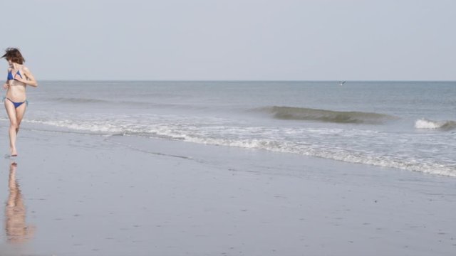 SLO MO, WS, Lockdown of a man with a squirt gun chasing a woman on the beach