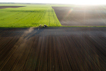 Aerial image of tractor working in field - obrazy, fototapety, plakaty