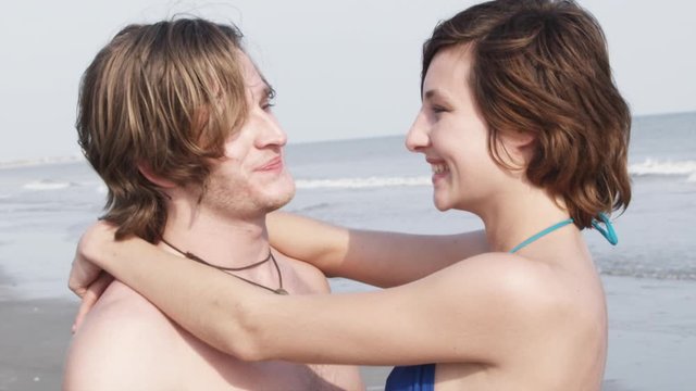 SLO MO, CU, PAN of a young affectionate couple at the beach