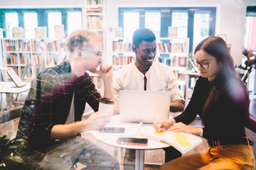 Cheerful diverse students around table in library