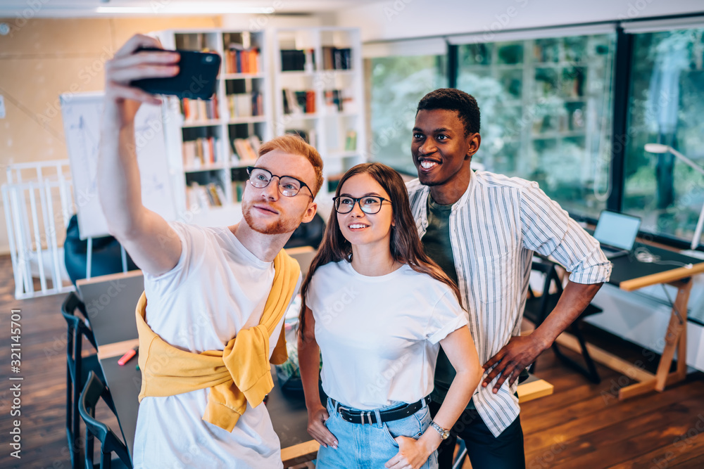 Sticker positive multiethnic colleagues taking selfie near table