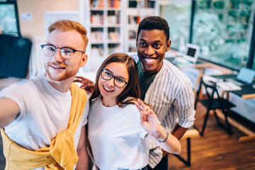 Optimistic diverse coworkers gesturing during selfie