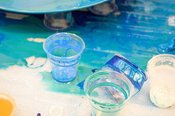 The process of creating a home-made trendy abstract modern pattern painted with a brush of acrylic blue multi-colored resin on a round wooden board