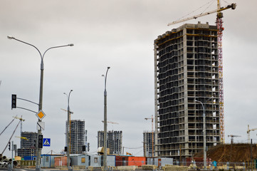 Fototapeta na wymiar Construction of large modern monolithic frame houses, buildings using industrial construction equipment and large high cranes. Construction of the building in the new micro district of the city