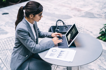 Elegant businesswoman typing on tablet working with statistics