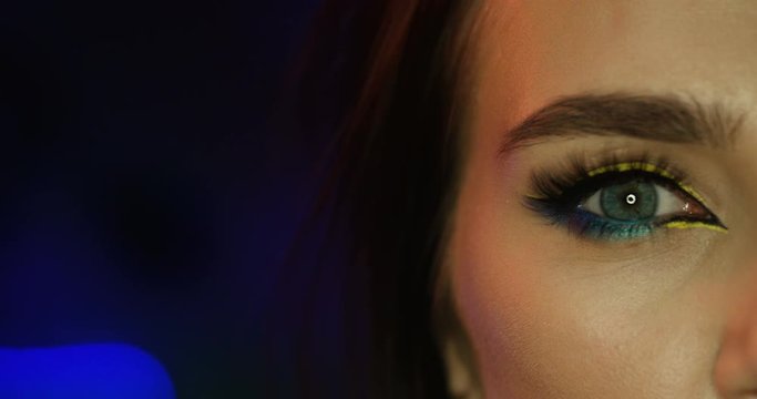 Close up of eye with colorful make up and glowing arrow of the beautiful woman. Macro shooting of female face. Caucasian brunette attractive woman opening eye.