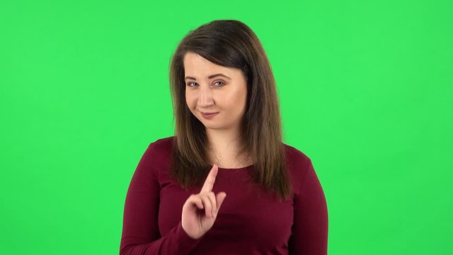 Portrait of pretty girl seductively smiling and gesture threatens by shaking her index finger. Green screen