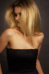 Naklejka premium portrait of a blonde on a gray Studio background, in a black dress with sequins