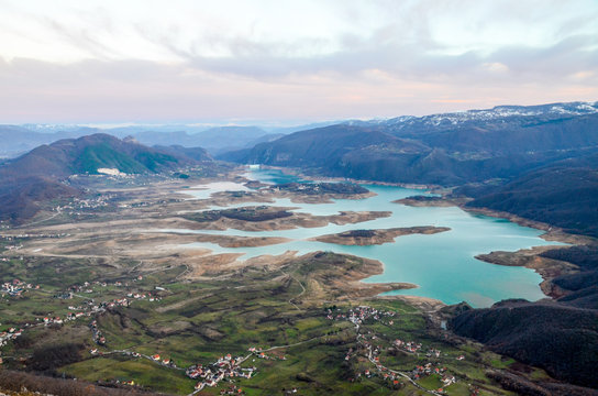 Aerial view of beautiful green lake and islands surrounded by mountains. Autumn landscape at evening. Large artificially formed lake at evening. Ramsko lake, Bosnia and Herzegovina.