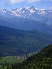 Mountain landscape of Svaneti on bright summer sunny day. Mountain lake, hills covered green grass on snowy rocky mountains background. Caucasus peaks in Georgia. Amazing view on wild georgian nature