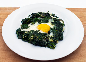 Plate of fried egg, mozzarella, and spinach on wooden table