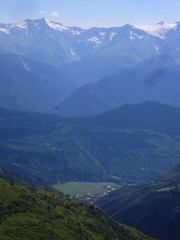 Mountain landscape of Svaneti on bright summer sunny day. Mountain lake, hills covered green grass on snowy rocky mountains background. Caucasus peaks in Georgia. Amazing view on wild georgian nature
