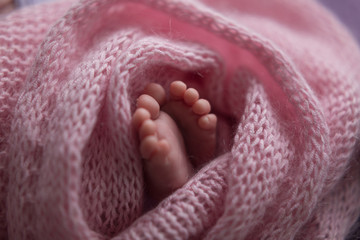 Little baby arms and legs.Baby in a basket on faux fur pink, soft focus