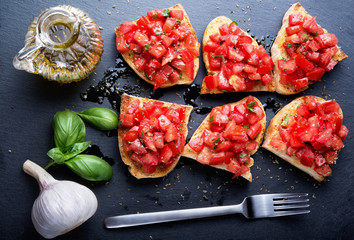 Tomato bruschetta on slate stone background. Top view.