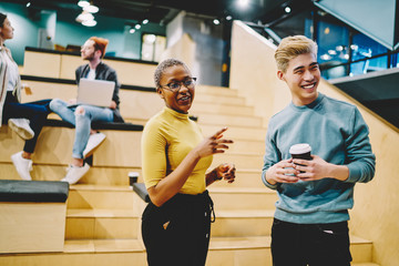 Cheerful diverse couple of students in university after lecture