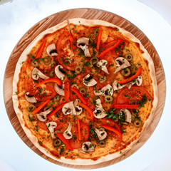 Pitzza with mushrooms on a wooden plate.