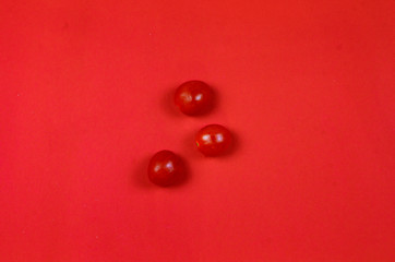 Photo top view of three small tomatoes on the red solid background