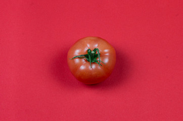 Top view and flat lay photo with one red natural eco tomato on the red solid background