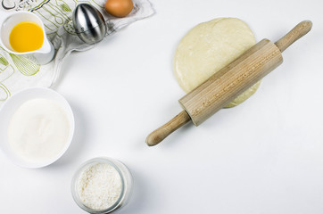 Baking ingredients and kitchen utensils on white background. eggs, sugar, flour, rolling pin and whisker. Cooking, baking, pastry or cookie cake ingredients