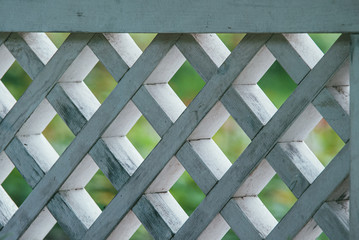 diamond-shaped wooden lattice painted white against the background of a green lawn