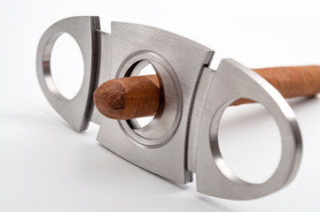 Cutting cigars and expensive luxury products concept with smooth hand rolled cigar in stainless...