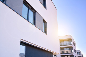 Modern multi story building being lit by the setting sun at afternoon. New apartment house residential building outdoor concept.