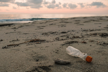 Plastic bottle waste on wild sea coast, sunset time,planet save, cilento italy 