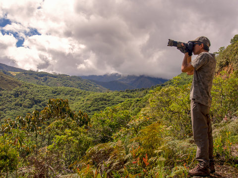 A photographer taking pictures of birds from the edge of mountain at the Paramo Chontales in the central Andean mountains of Colombia.