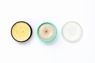 Top view of a black turquoise and white jars with different cream on a white background. The concept of beauty, medicine, facial and body skin care, hair care