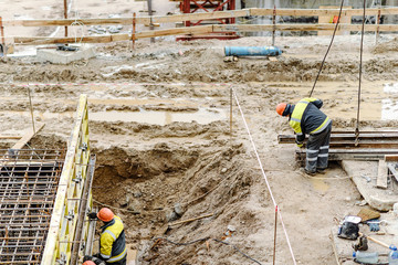worker installing a heavy lifting sling onto a crane. workers in the mud on a construction site. hard working conditions. hard work