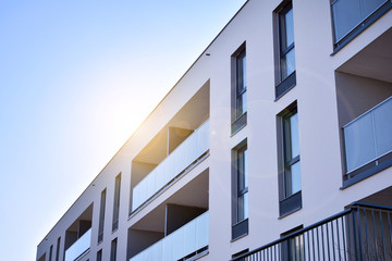 Modern multi story building being lit by the setting sun at afternoon. New apartment house residential building outdoor concept.