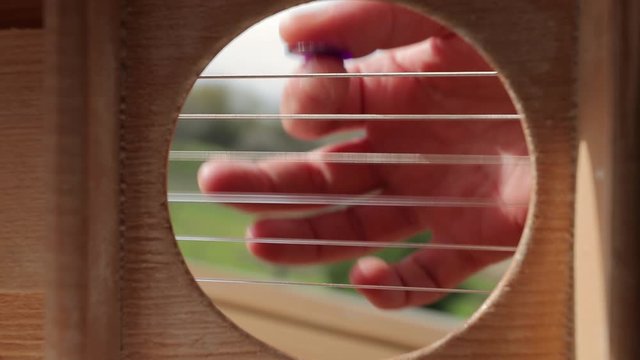 Playing acoustic guitar viewed from the inside, strumming chords with pick, slow motion from 120 fps, unusual, weird perspective, vibrating strings, fullframe camera