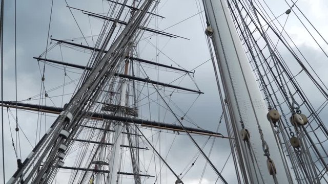 Close-up of the rigging and mast of Cutty Sark ship against the blue cloudy sky. Action. Greenwich, London