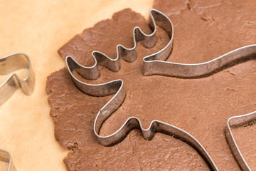 A moose-shaped cookie mold lies on a small rolled piece of brown dough