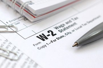 The pen and notebook on the tax form W-2 Wage and Tax Statement. The time to pay taxes