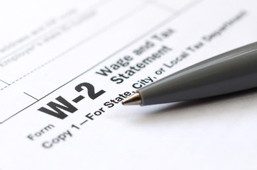 The pen lies on the tax form W-2 Wage and Tax Statement. The time to pay taxes