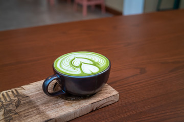 Hot matcha green tea l;atte art on wooden table