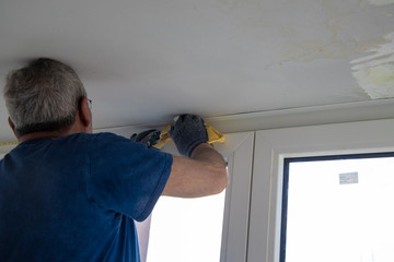 Handyman carpenter painter renovating terrace and assembling glass windows with tools work in progress: skimming compound glue gun cutter electric saw batten sandpaper emery cloth white roller ladders