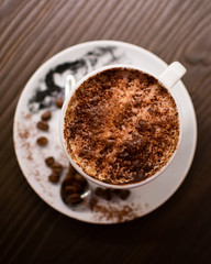 Café Capuccino sobre un plato con fondo de madera y granos de café alrededor