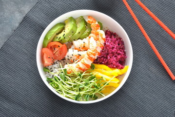Fresh seafood recipe. Shrimps poke bowl with rice, red cabbage,avocado,yellow sweet pepper. Food concept poke bowl on gray background