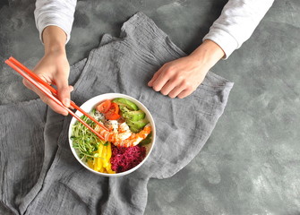 Fresh seafood recipe. Shrimps poke bowl with rice, red cabbage,avocado,yellow sweet pepper. Food concept poke bowl on gray background