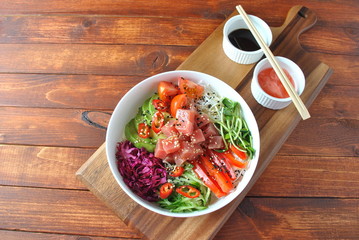 Organic food. Fresh seafood recipe. Tuna poke bowl with crystal noodles, fresh red cabbadge, avocado, cherry tomatoes. Food concept poke bowl on wooden background