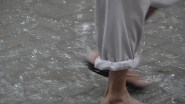 two humans are walking in a puddle when it rains